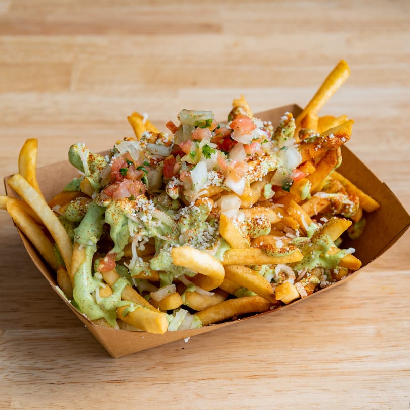 El Barrio's Mexican street fries, topped with green sauce, pico de gallo, and cotija cheese.