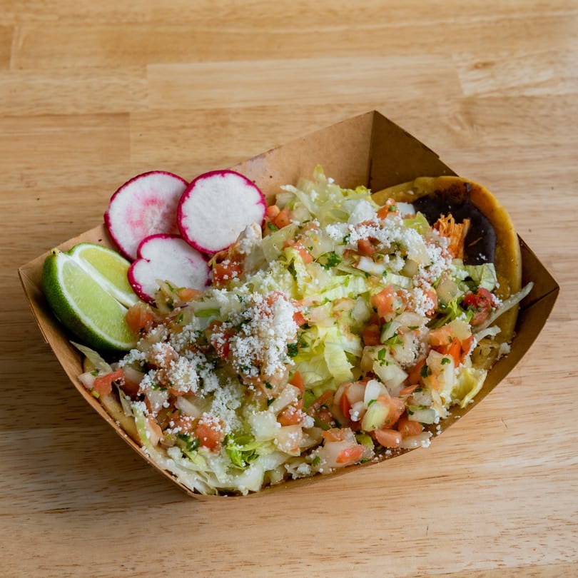 El Barrio Neighborhood Tacos' tostada with lettuce, pico de gallo, cheese, lime, and radishes.